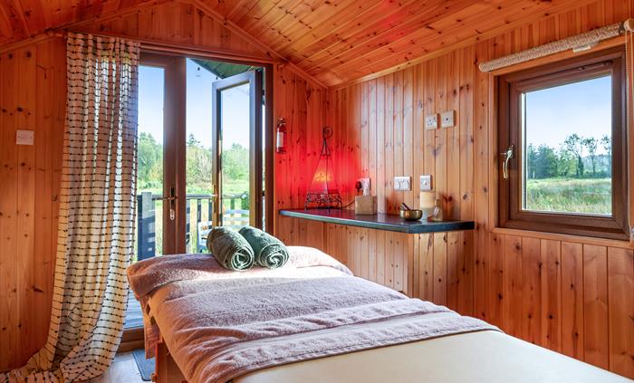 Holistic therapy cabin with a massage table and a view of the meadow in the background